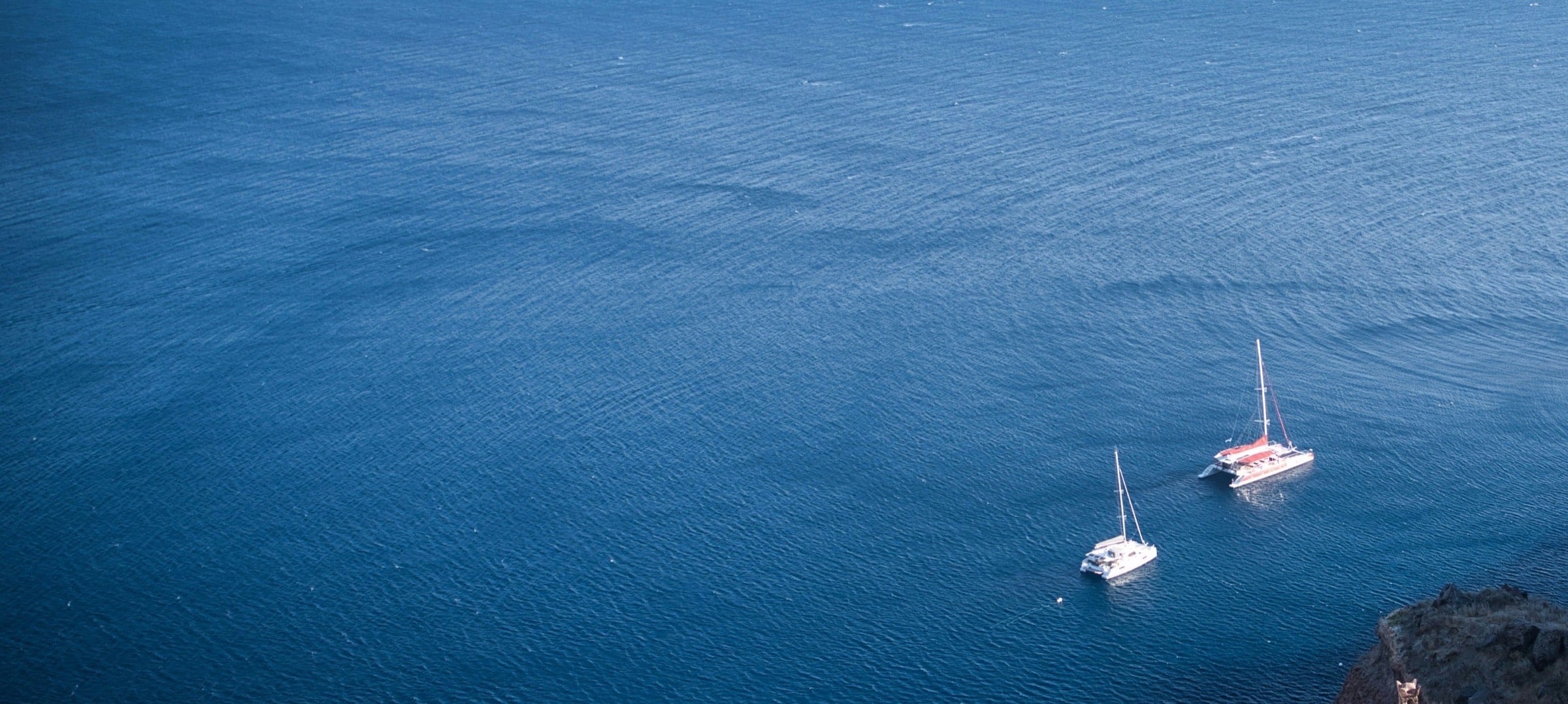 Open water of the Aegean — two sailboats at anchor