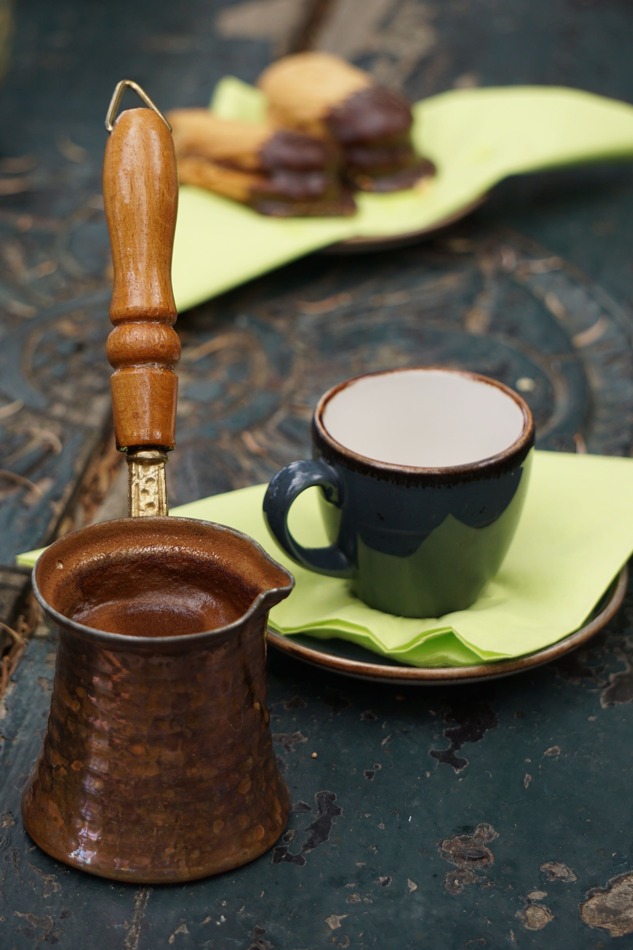 Greek coffee the old way — a hammered copper briki and a small cup on a weathered taverna table in Litochoro, Greece.