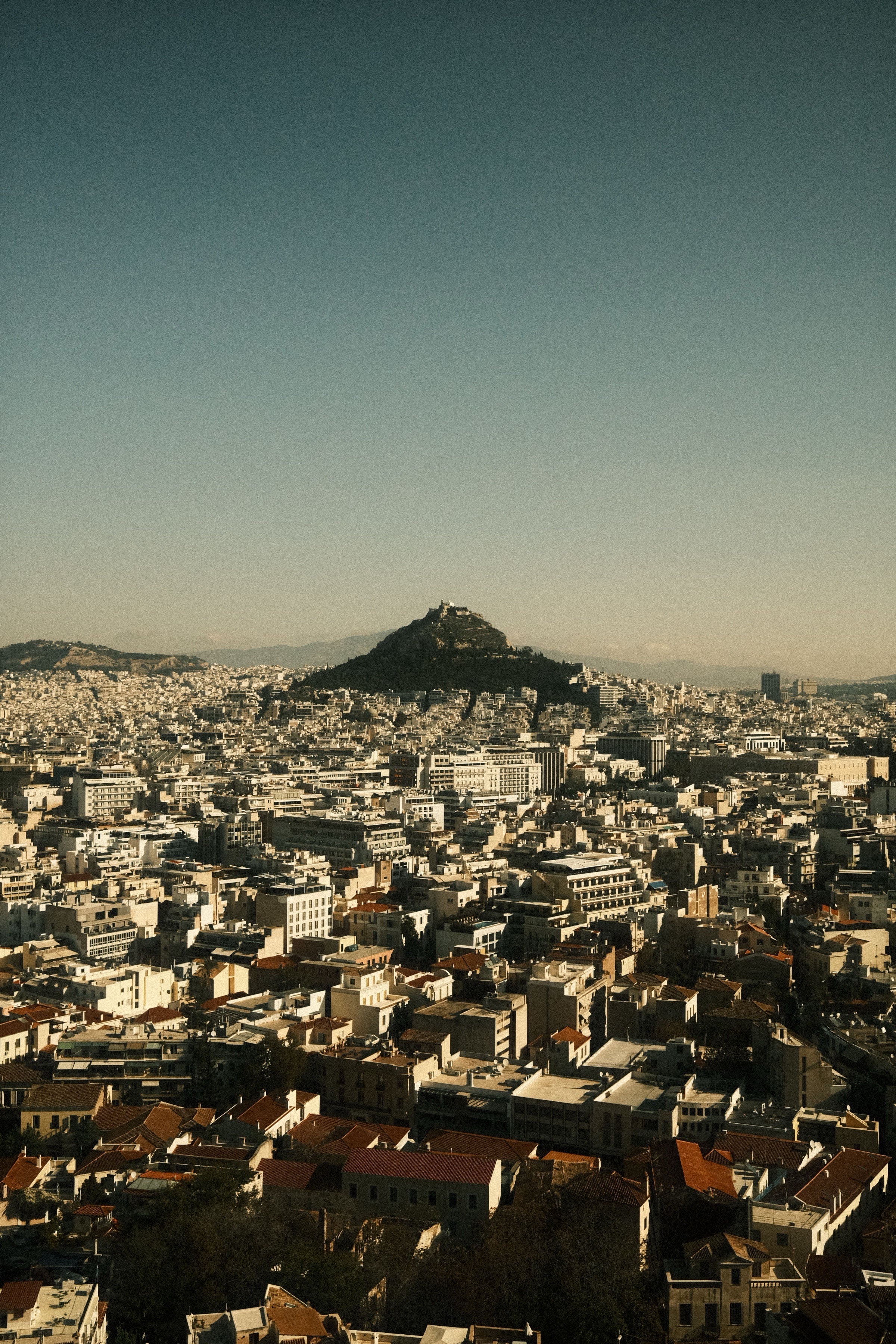 Lycabettus hill rising above the rooftops of central Athens at sunrise — the hill that stands directly over the Mavromichali quarter.
