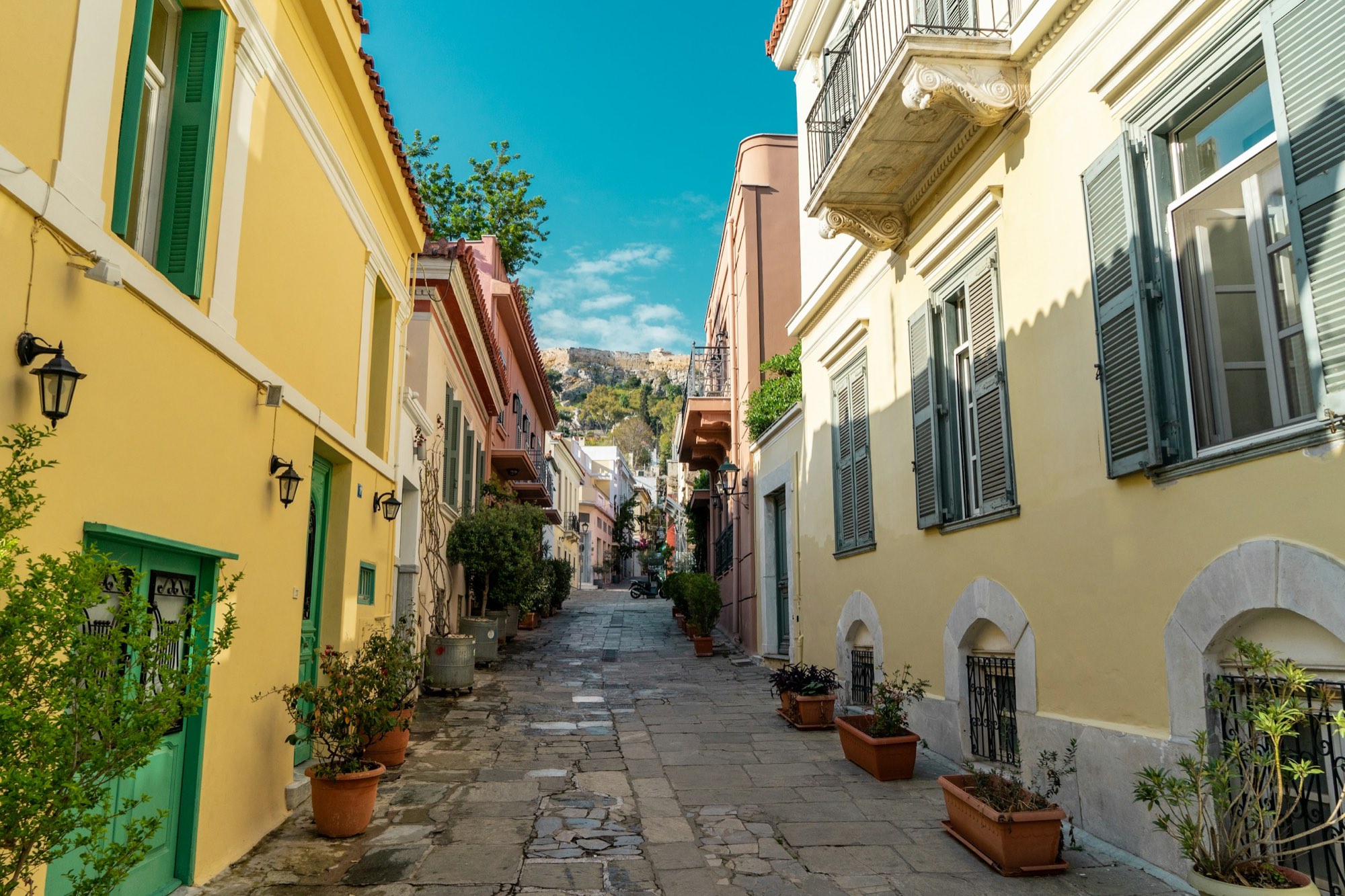 An empty lane in Plaka, Athens at morning light, potted plants along the walls