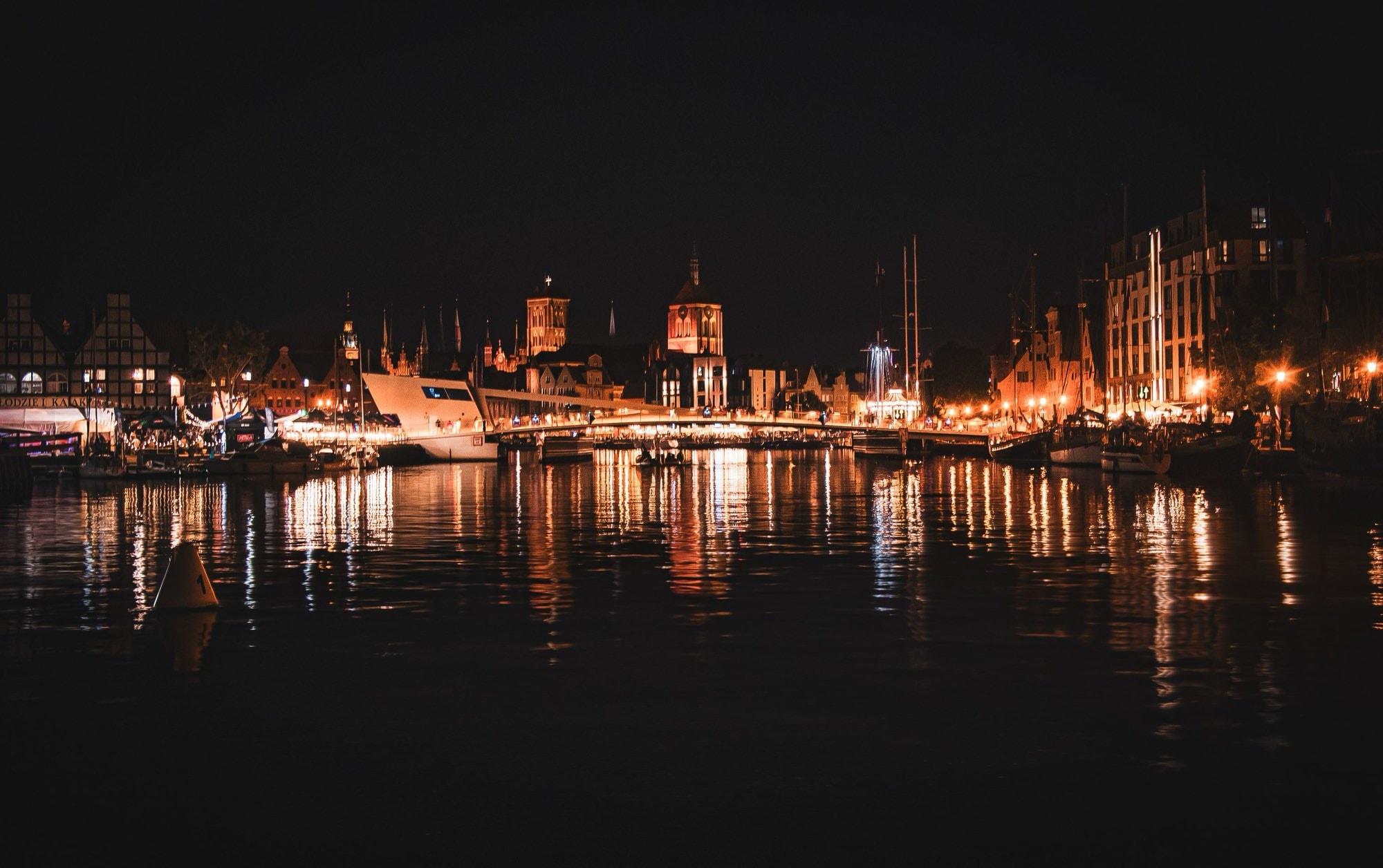Gdańsk's Old Town at night — the lit gabled waterfront houses and their reflections in the Motława river